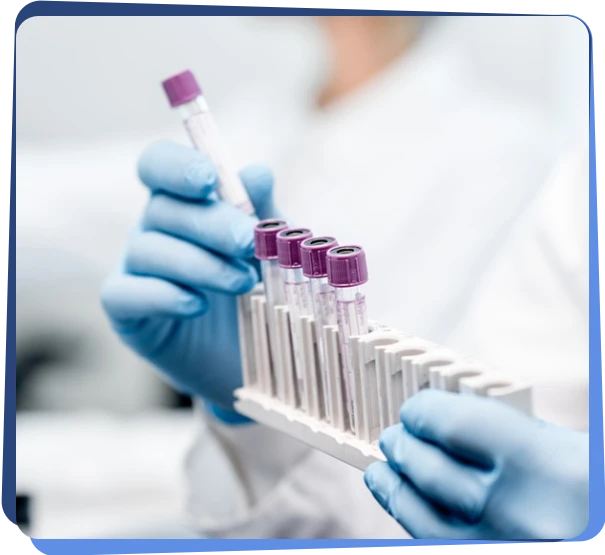 Gloved hands holding blood sample tubes in a laboratory